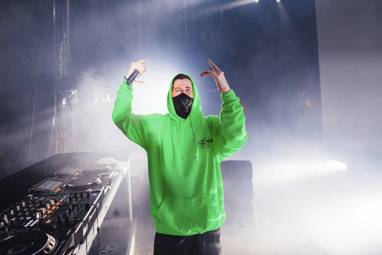 Alan Walker energizing the crowd, sporting the green Stage Hoodie at a live music event.