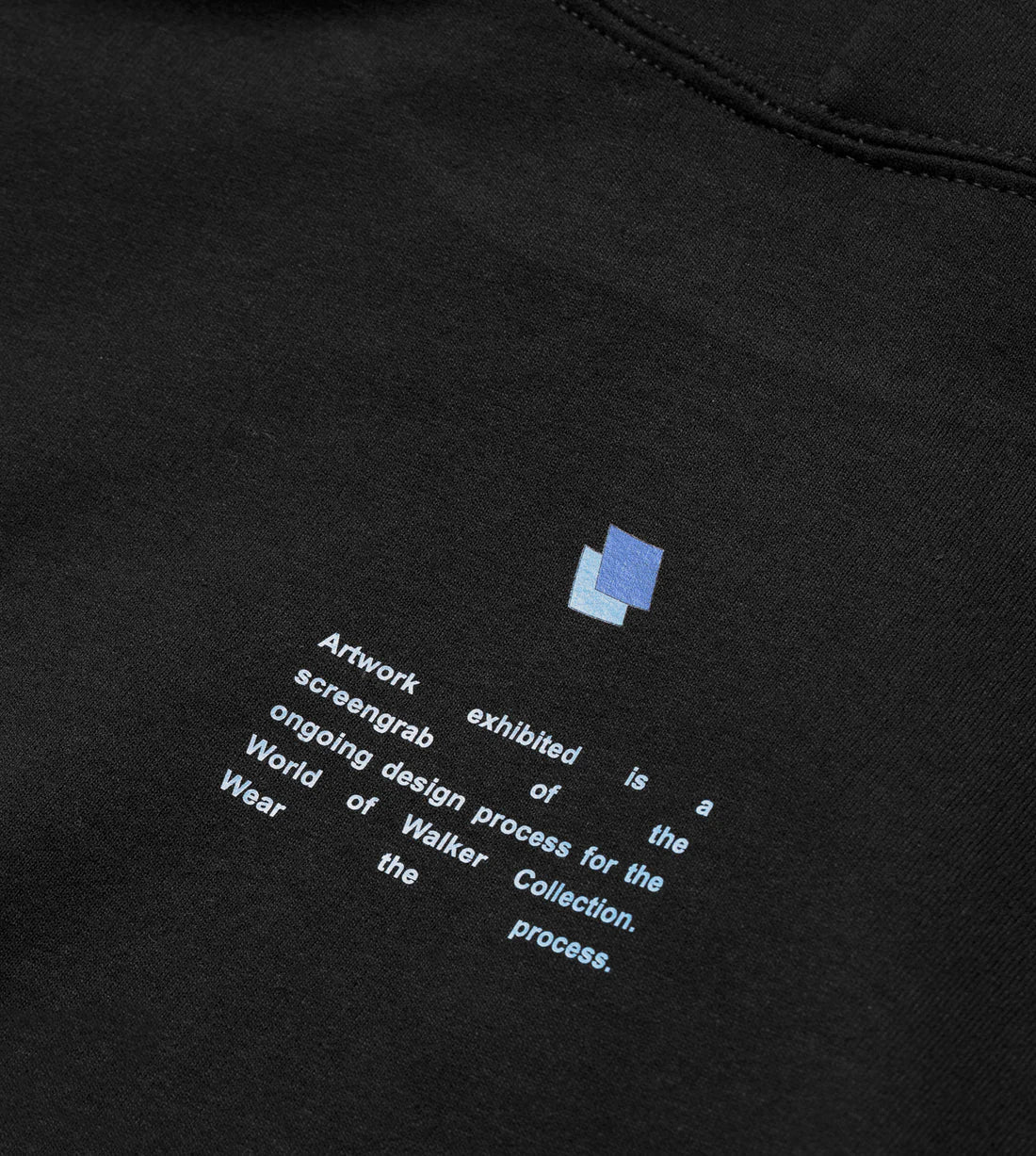 Close-up of the Alan Walker Blueprint Hoodie with printed statement about the design process on the World of Walker Wear Collection, accompanied by a small blue logo patch.