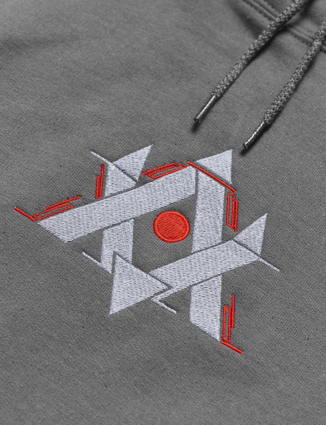Detailed embroidery of a geometric gaming motif in red and white on a soft gray hoodie, offering a subtle nod to gamer identity.